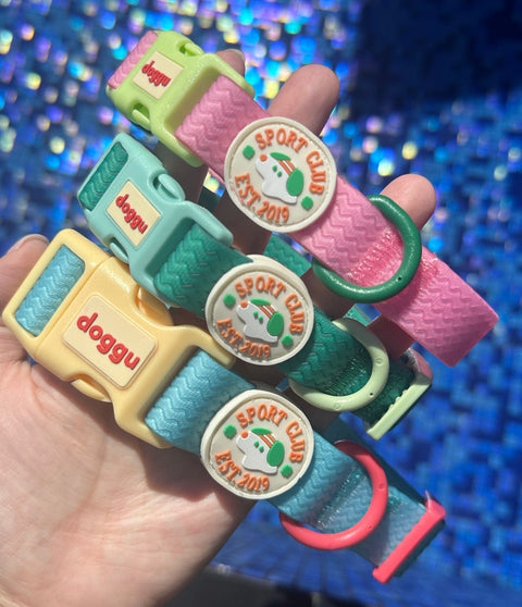 Three Doggu Sport Club waterproof dog collars showing the round cream SPORT CLUB EST. 2019 crest